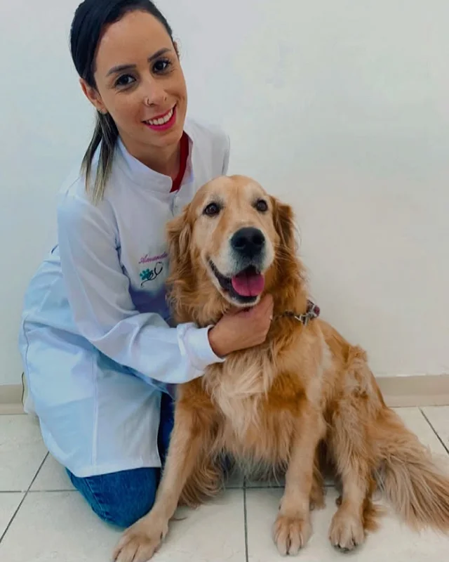 A Dra. Amanda agachada ao lado de um golden retriever