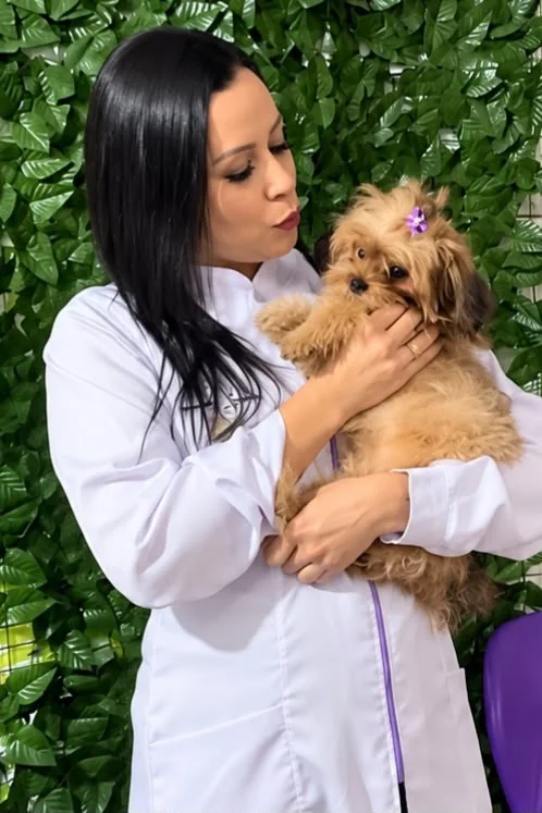 A Dra. Amanda S. Souza de jaleco branco, com um cachorro no colo